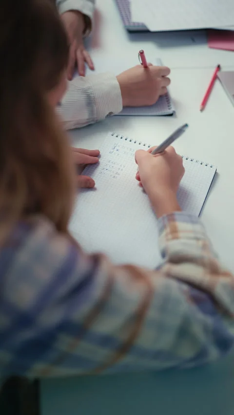 A schoolgirl writes a math equation in her notebook during a lesson at school Stock Footage 300277768