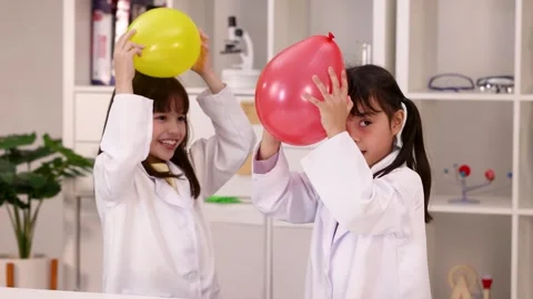 Schoolgirls in Lab Coats Perform Static Electricity Experiment with Balloons Stock-Footage 342714291