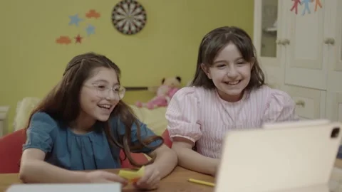 Schoolgirls study online using tablet computer taking notes in notebook. Video stock 202889934