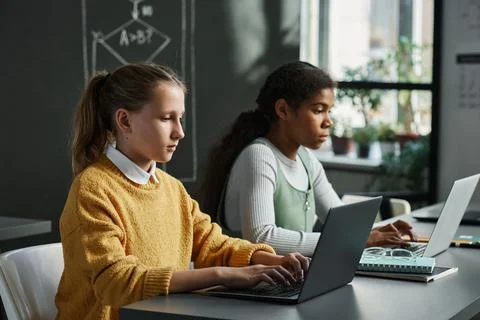 Schoolgirls typing on computers at class Stock Photos