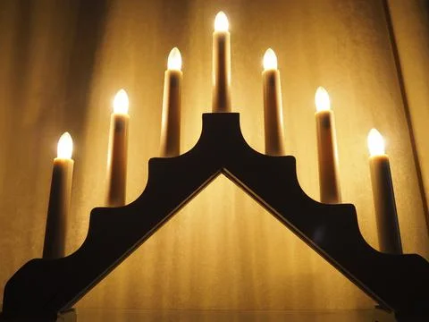 Schwibbogen arch luminaire in the form of a triangular candlestick. Yellow backg Stock Photos