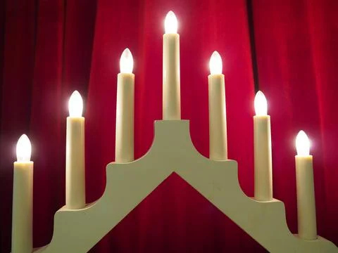 Schwibbogen arch luminaire in the form of a triangular candlestick. Red backgrou Stock Photos