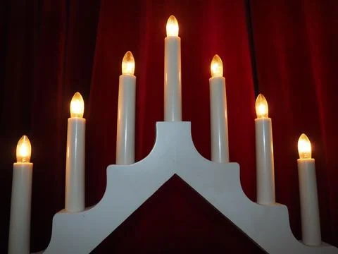 Schwibbogen arch luminaire in the form of a triangular candlestick. Red backgrou Stock Photos