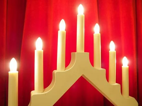 Schwibbogen arch luminaire in the form of a triangular candlestick. Red backgrou Stock Photos
