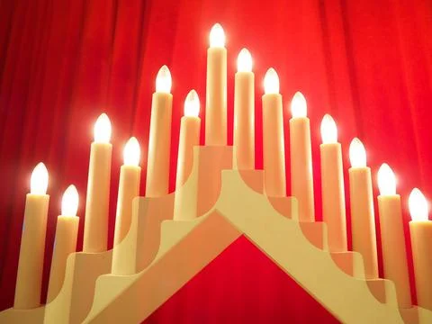 Schwibbogen arch luminaire in the form of a triangular candlestick. Red backg Stock Photos