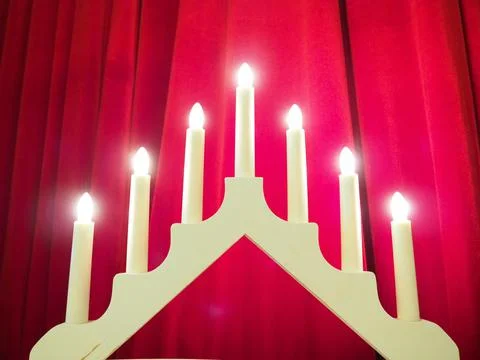 Schwibbogen arch luminaire in the form of a triangular candlestick. Red backg Stock Photos