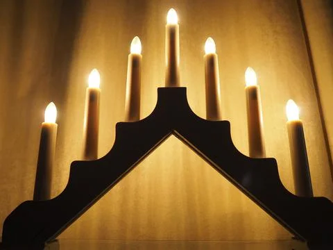 Schwibbogen arch luminaire in the form of a triangular candlestick. Yellow ba Stock Photos
