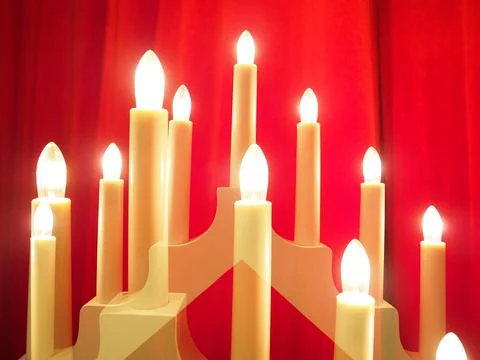 Schwibbogen arch luminaire in the form of a triangular candlestick. Red backg Stock Photos
