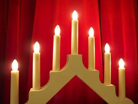 Schwibbogen arch luminaire in the form of a triangular candlestick. Red backg Stock Photos