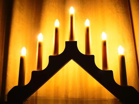Schwibbogen arch luminaire in the form of a triangular candlestick. Yellow ba Stock Photos