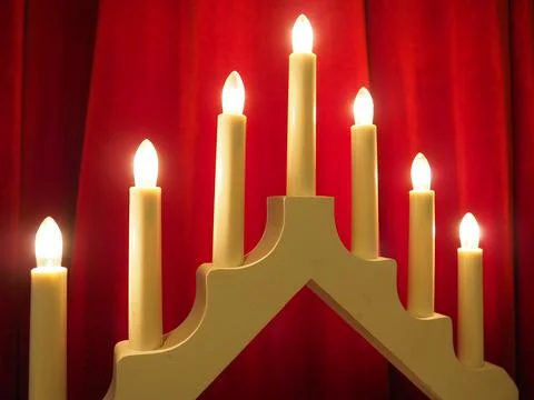 Schwibbogen arch luminaire in the form of a triangular candlestick. Red backg Stock Photos
