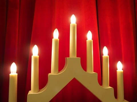 Schwibbogen arch luminaire in the form of a triangular candlestick. Red backg Stock Photos