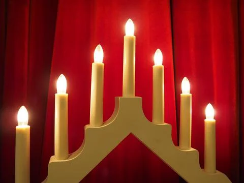 Schwibbogen arch luminaire in the form of a triangular candlestick. Red backg Stock Photos
