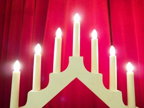 Schwibbogen arch luminaire in the form of a triangular candlestick. Red backg Stock Photos