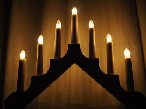 Schwibbogen arch luminaire in the form of a triangular candlestick. Yellow ba Stock Photos
