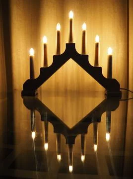 Schwibbogen arch luminaire, a triangular candlestick on glass table. Yellow b Stock Photos
