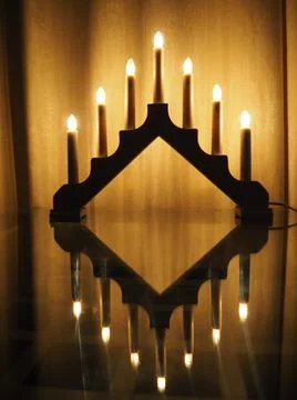 Schwibbogen arch luminaire, a triangular candlestick on glass table. Yellow b Stock Photos