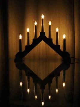 Schwibbogen arch luminaire, a triangular candlestick on glass table. Yellow b Stock Photos