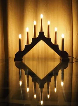 Schwibbogen arch luminaire, a triangular candlestick on glass table. Yellow b Stock Photos