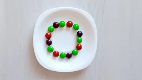 Science experiment for kids. Circle of colored candies on white plate. Stock Footage 139134794