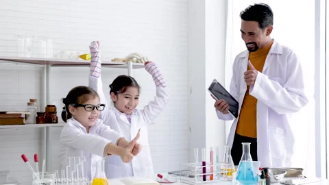 Science teacher and elementary pupils in white gowns workshop training in c.. Stock Footage 243555320