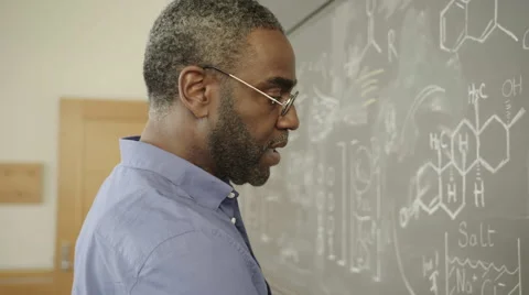 Science Teacher Writes Equations on Chalk Board HD Vídeos de archivo 60989184