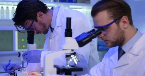Science Team of Biochemists Examining on Microscopes Bacteria in Laboratory Room Stock Footage 81465288