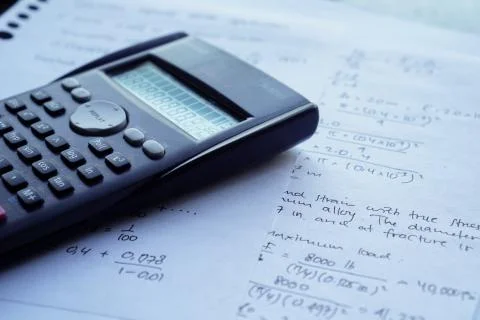 Scientific math workout. sheet paper with solving equation math next to calcu Stock Photos
