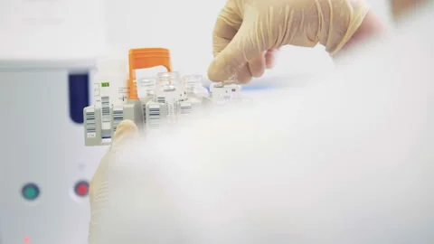 Scientific worker is turning test tubes and putting them into a laboratory Stock Footage 87819261