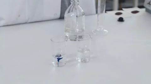 Scientist add blue substance to the transparent liquid in glass bulb and mix it Stock Footage 201344811