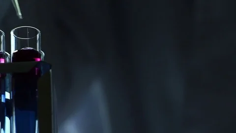 Scientist adds reagents into  vials on dark background Stock Footage 77208978