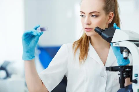 Scientist analyzing microscope slide at laboratory. Female Working in Laboratory Stock Photos