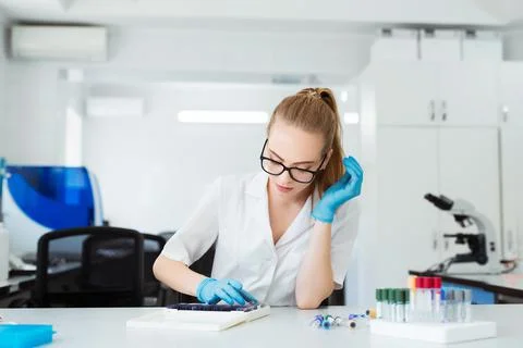 Scientist analyzing microscope slide at laboratory. Female Working in Laboratory Stock Photos