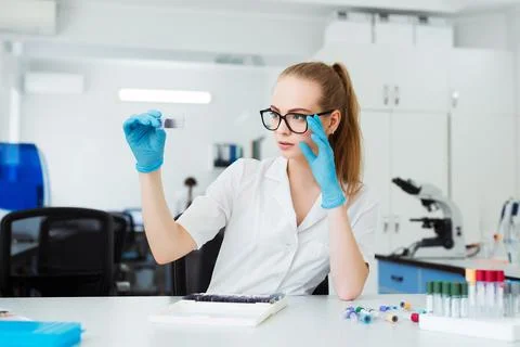 Scientist analyzing microscope slide at laboratory. Female Working in Laboratory Stock Photos