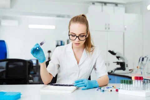Scientist analyzing microscope slide at laboratory. Female Working in Laboratory Stock Photos