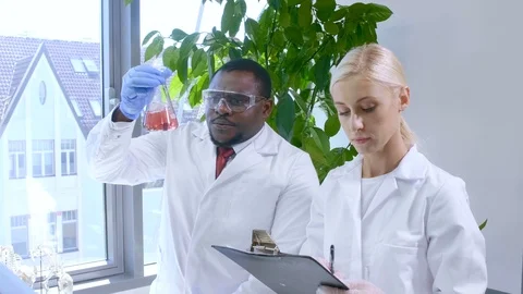 Scientist and his assistant working in lab. Doctor teaching intern to make Stock Footage 115877784