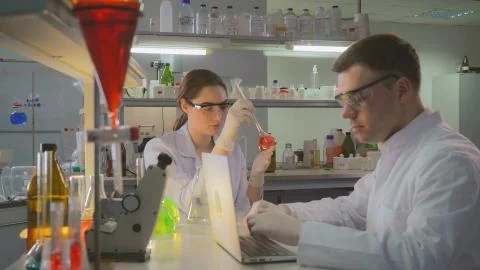Scientist with assistant working in laboratory in the evening. Stock Photos