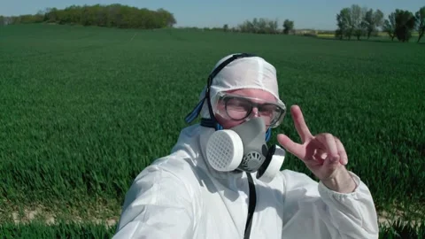 Scientist biologist in a cornfield makes a pose in a mask and protective suit fo Video stock 154237027