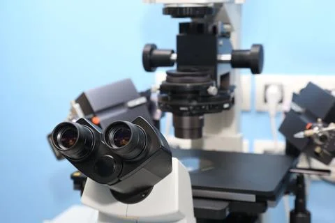 A scientist in a blue cap examines a sample under a high-tech microscope in.. Fotos de archivo