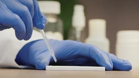 Scientist in blue gloves performing rapid antigen diagnostic test using pip.. Stock Footage 334828723