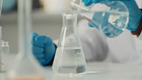 A scientist carefully pouring a liquid into a laboratory flask 库存影片 314933991