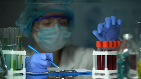Scientist checking tube with blood analysis and making notes, epidemic outbreak Stock Footage 104990797