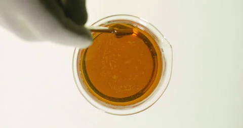 Scientist chemist pouring engine oil from glass into beaker., Top view Stock Footage 338438681
