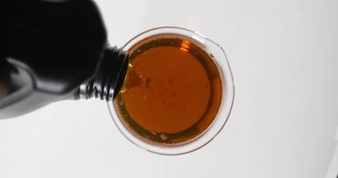 Scientist chemist pouring engine oil from glass into beaker. Stock Footage 339267693