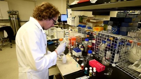 Scientist in chemistry lab adding compound to flask and inspecting contents. Stock-Footage 82841592