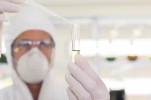 Scientist in clean suit using pipette and test tube in laboratory Stock Photos