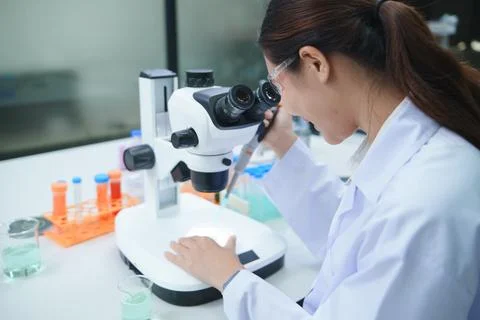 Scientist Conducting Chemical Experiment Using Microscope and Pipette in Stock-Fotos