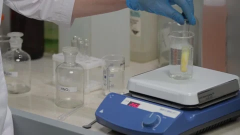 Scientist Conducting Lab Experiment with Beaker and Heating Plate Stock Footage 302888486