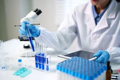 Scientist conducting laboratory experiment analyzing blue liquid in test tu.. Stock Photos