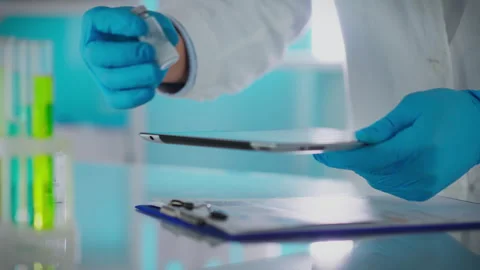 Scientist conducting research with tablet and test tubes in laboratory setti Stock Footage 295160847